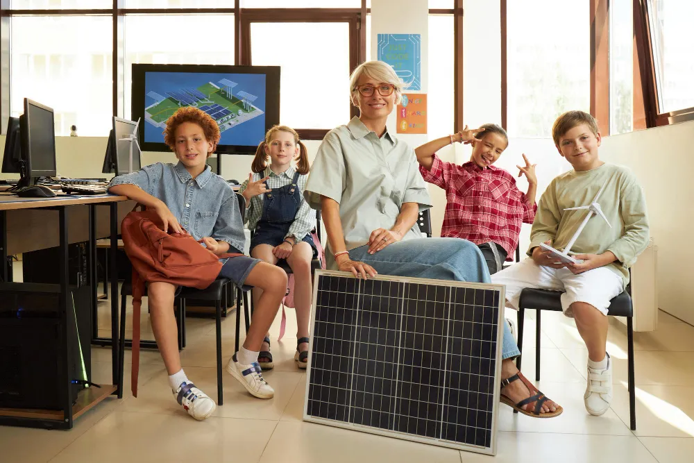 panel fotowoltaiczny trzymamy przez nauczycielkę wśród dzieci