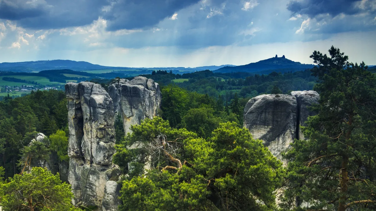 Skalne miasto w Czechach, z majestatycznymi formacjami skalnymi i bujną zielenią, na tle malowniczego krajobrazu.
