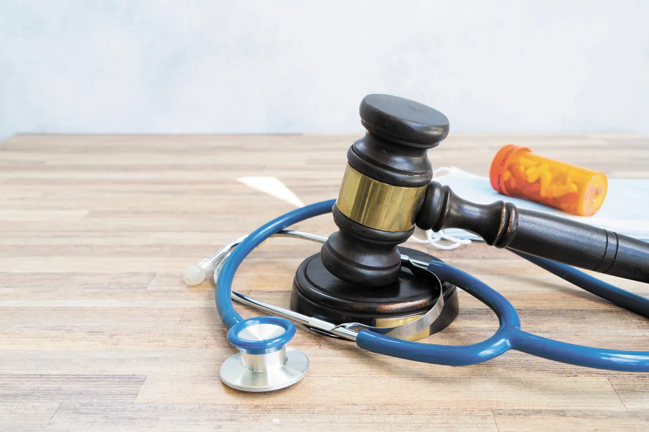 Młotek sędziowski, stetoskop i buteleczka z lekami symbolizują testament życia i jego kruchość.