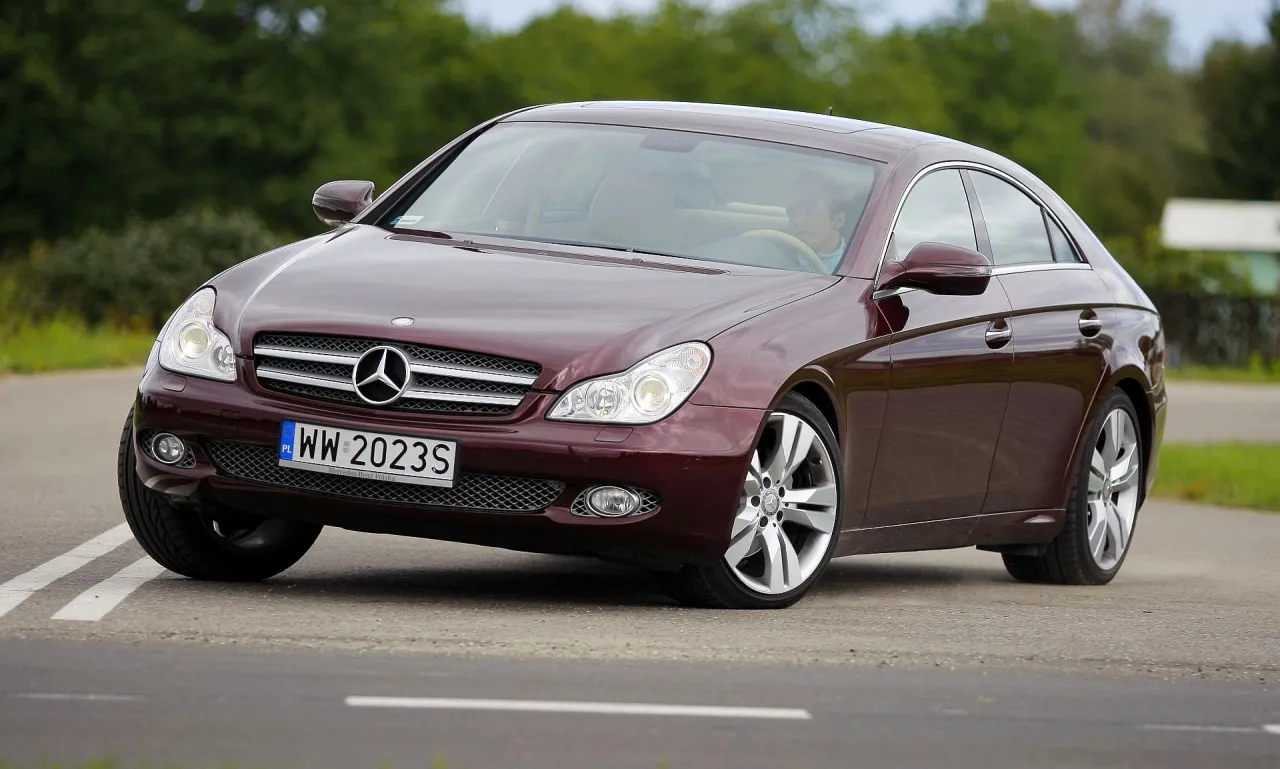Elegancki, bordowy Mercedes CLS 63 AMG na zakręcie drogi, z widocznym kierowcą.