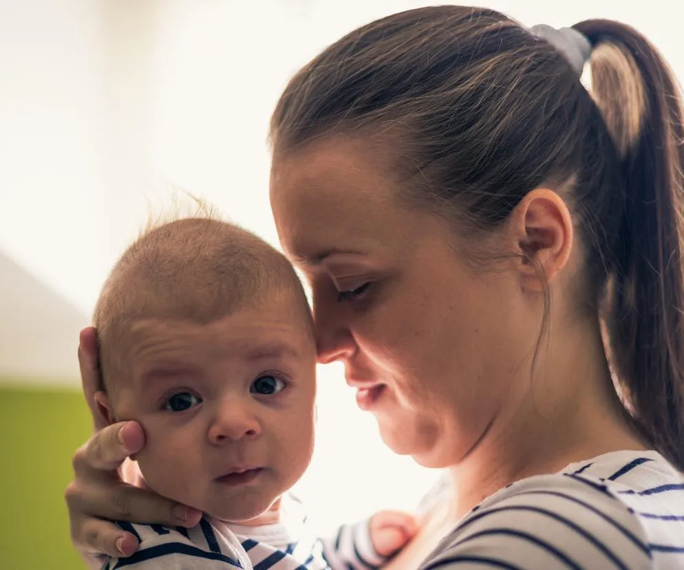 rodzic przytulający marudne niemowlę w domu