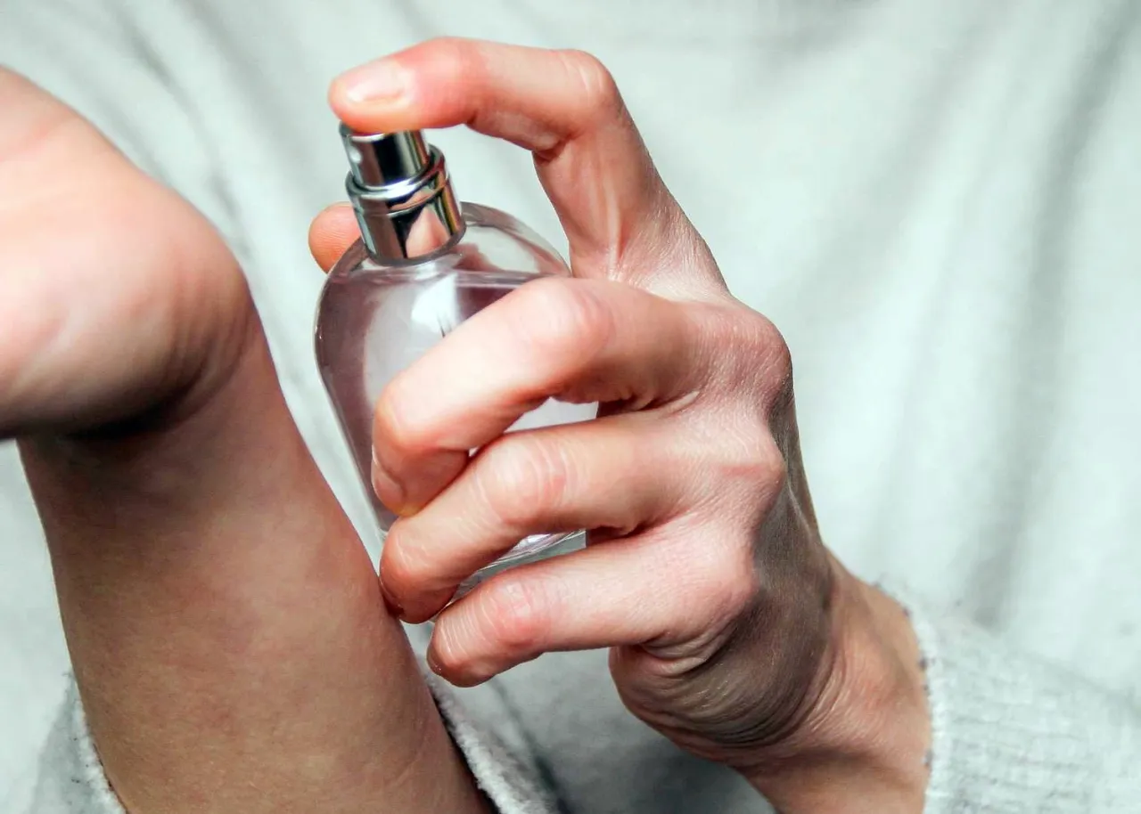 Dłoń aplikuje perfumy na nadgarstek. Wybór między trwalsza woda toaletowa czy perfumowana to klucz do długotrwałego zapachu.