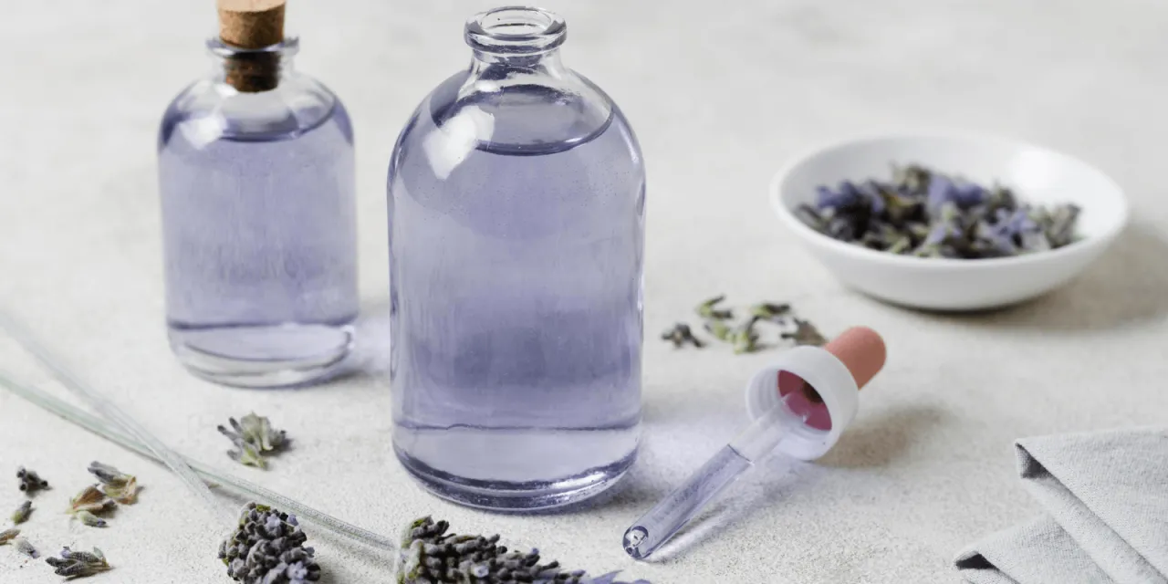 Dwie buteleczki z fioletowym płynem, suszona lawenda i pipeta. Czy olejek lawendowy odstrasza kleszcze?