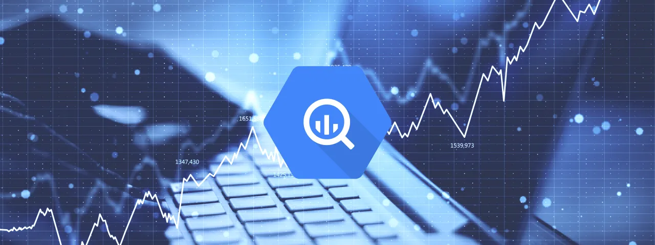 Niebieska ikona z lupą i wykresem symbolizuje analizę danych w BigQuery. W tle widać klawiaturę i wykresy finansowe.