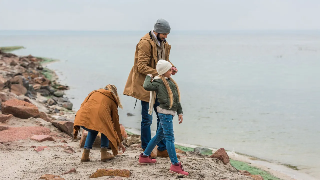 Rodzina na zimowej plaży z dziećmi szukającymi bursztynu