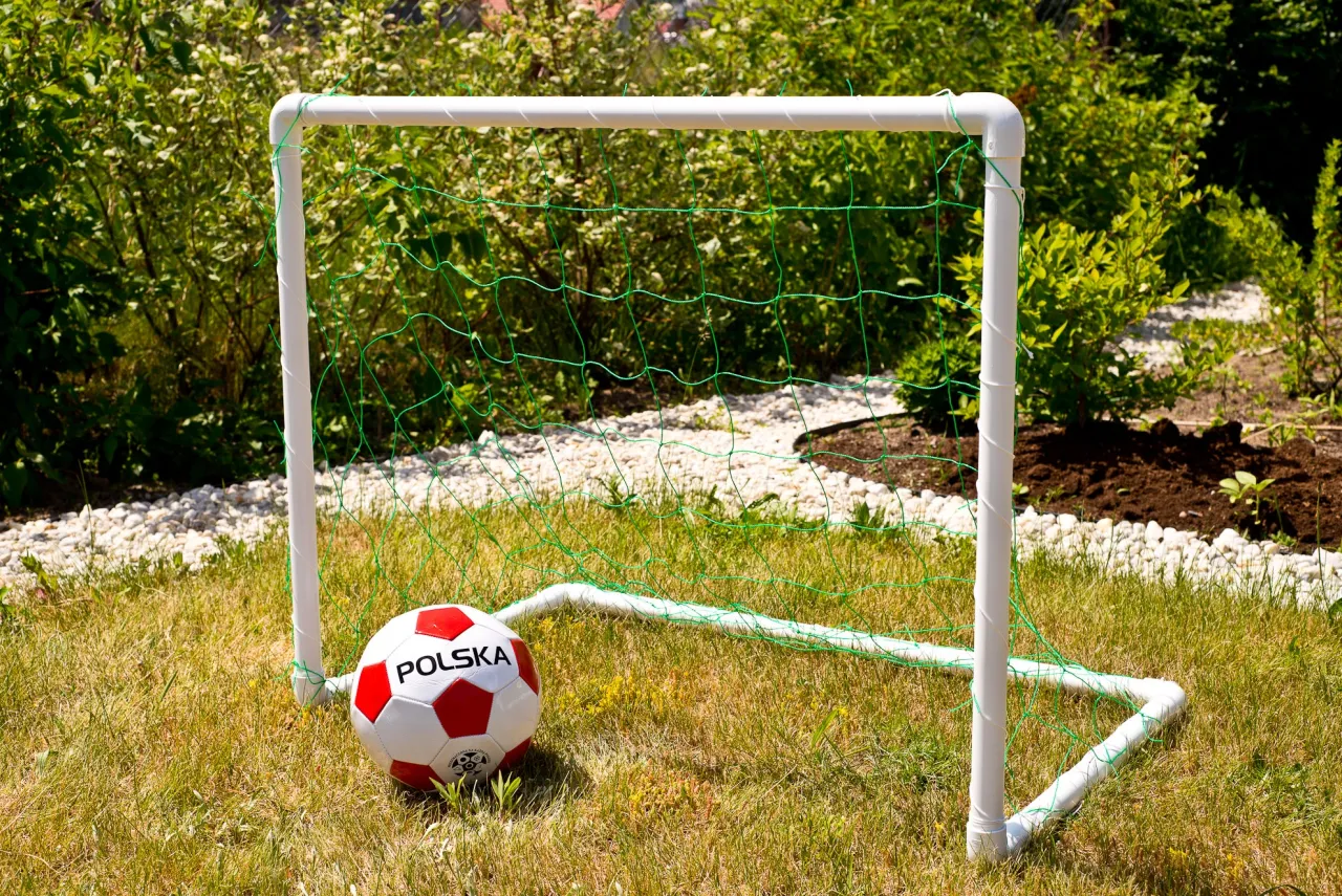 Bramka do piłki nożnej z rurek PCV i siatki. Piłka z napisem 