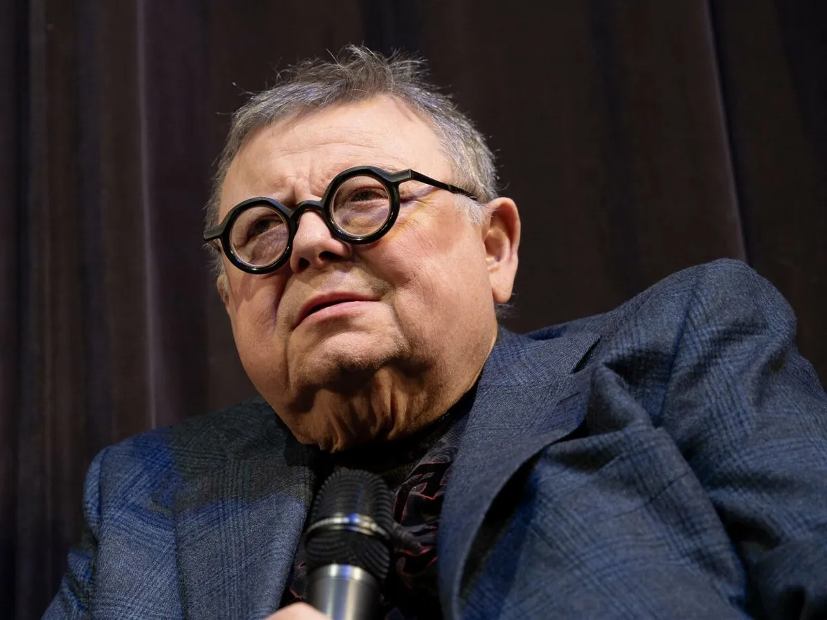 Wojciech Mann w okularach, w garniturze, z mikrofonem. Ile lat ma Wojciech Mann?