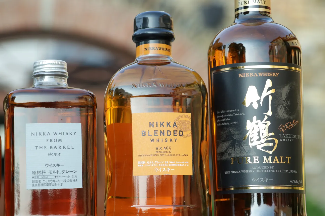 Trzy butelki whisky Nikka. Zwróć uwagę na zmętnienie i osad w starych butelkach, by rozpoznać objawy zepsutej whisky.