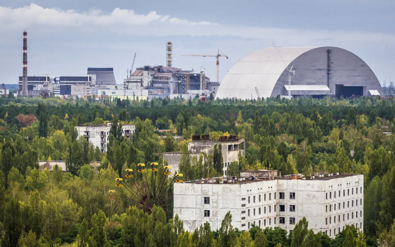 Widok na Czarnobylską Elektrownię Jądrową z nową osłoną i opuszczonym miastem Prypeć. Czy reaktor w Czarnobylu jest aktywny? Nie, ale jego historia wciąż żyje.