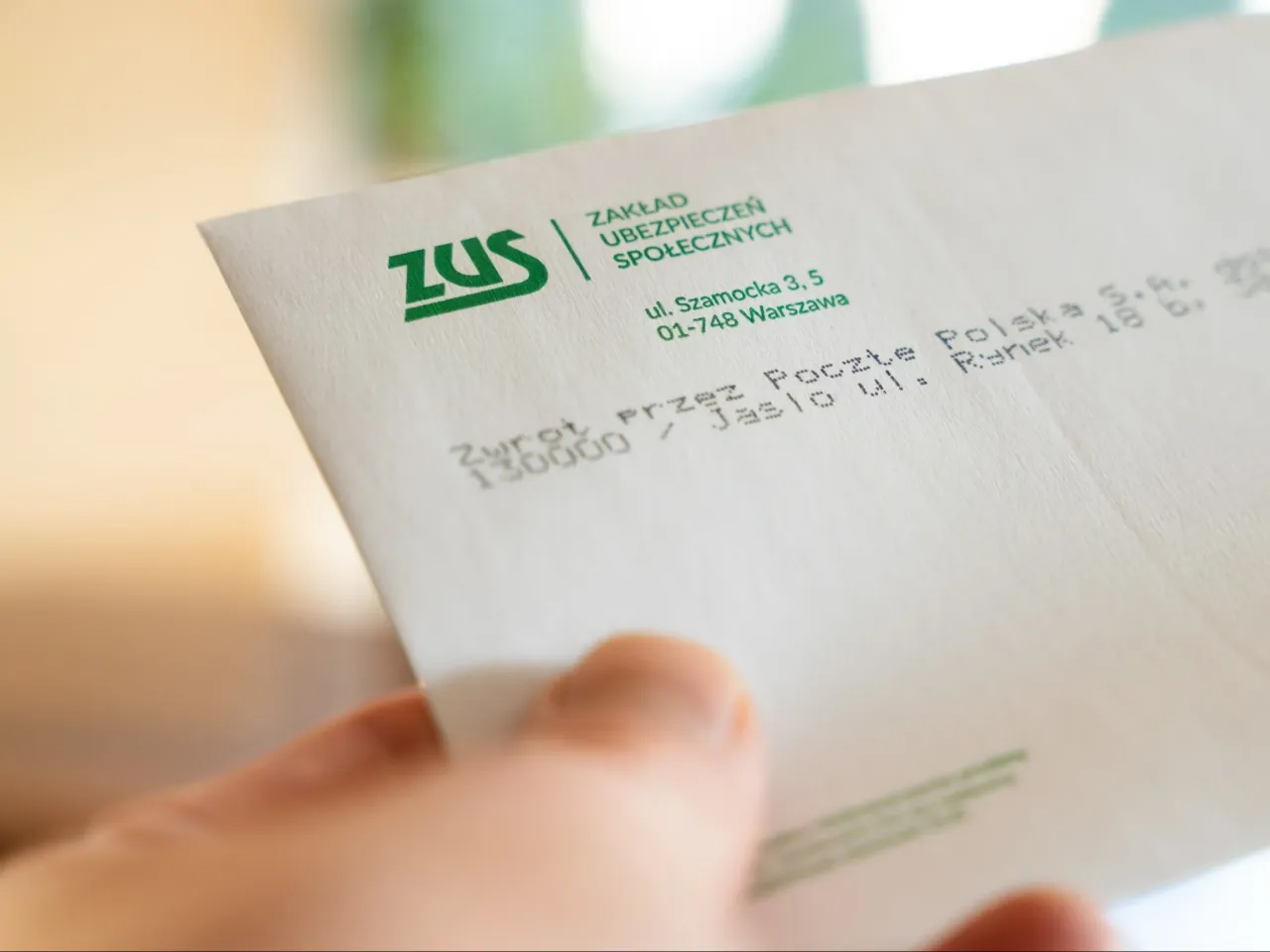 Dłoń trzyma dokument ZUS. Czy szkoła zawodowa wlicza się do lat pracy? ZUS odpowie na to pytanie.