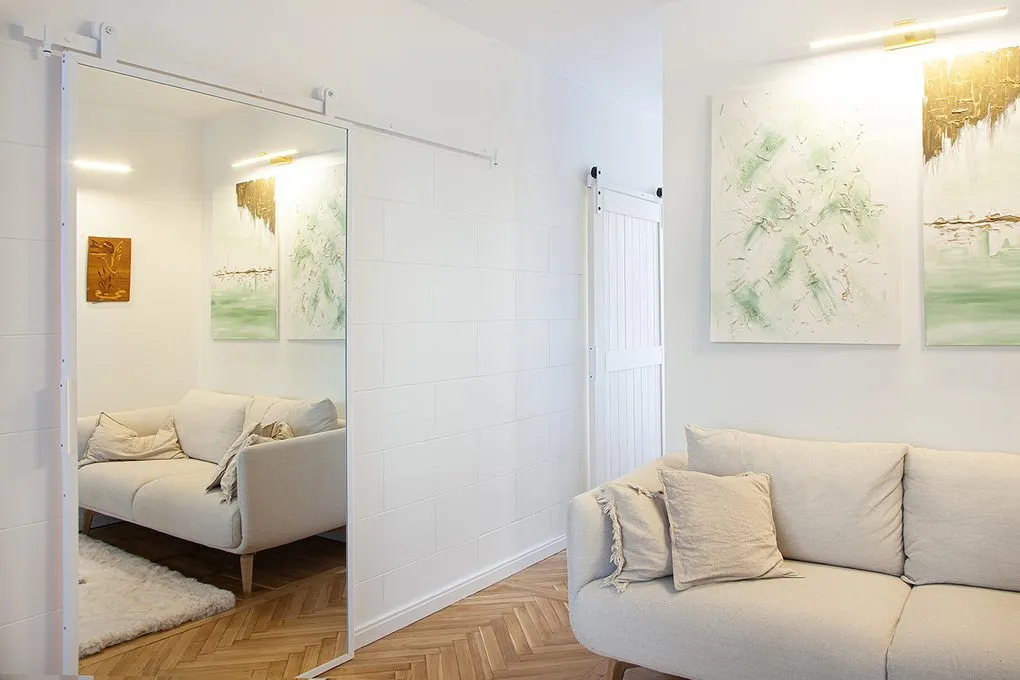 Jasne wnętrze małego mieszkania z lustrami i wielopunktowym oświetleniem