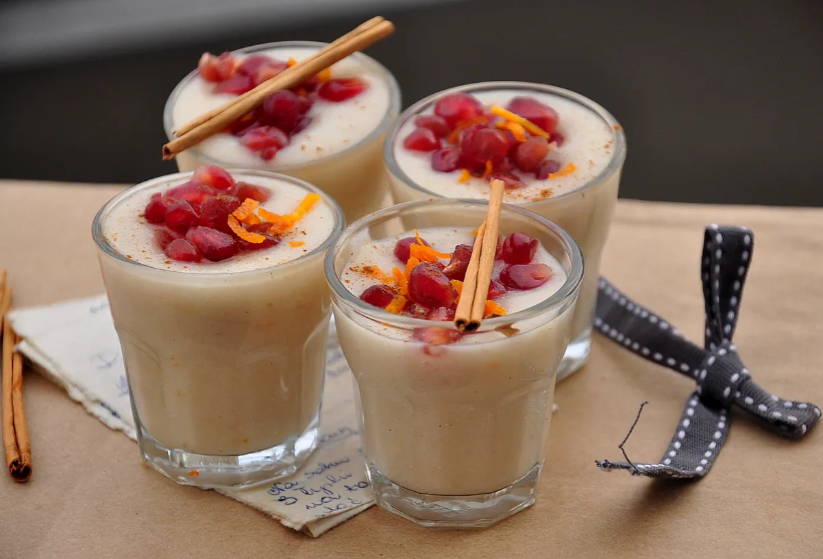 Pyszny deser z ugotowanego ryżu, ozdobiony granatem, sk&oacute;rką pomarańczy i laską cynamonu. Idealny pomysł na wykorzystanie resztek ryżu!