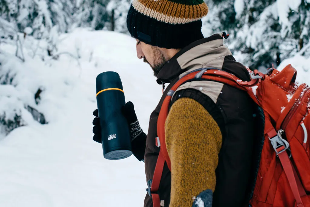turysta pije z termosu w g&oacute;rach