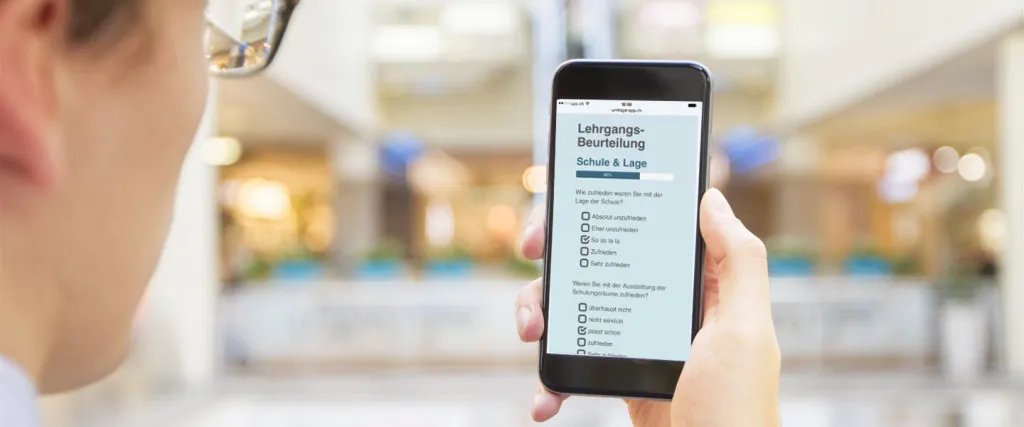 Smartphone in der Hand einer Person, auf dem Bildschirm ist eine Umfrage-App zu sehen
