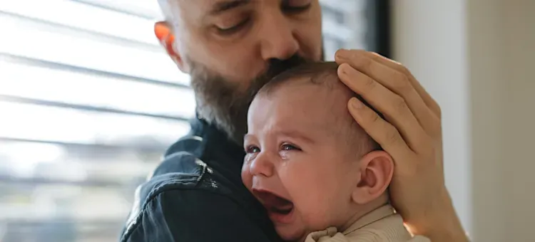 rodzic przytulający płaczące niemowlę