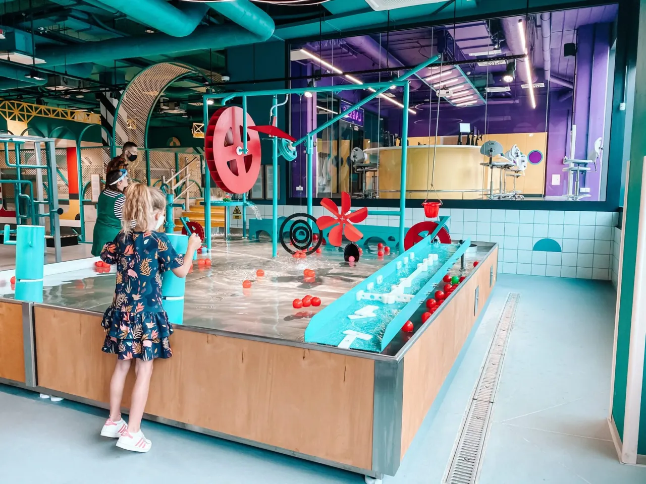 Interaktywne atrakcje dla dzieci w Białymstoku: dziewczynka bawi się w wodnym placu zabaw z kulkami i kołami wodnymi.