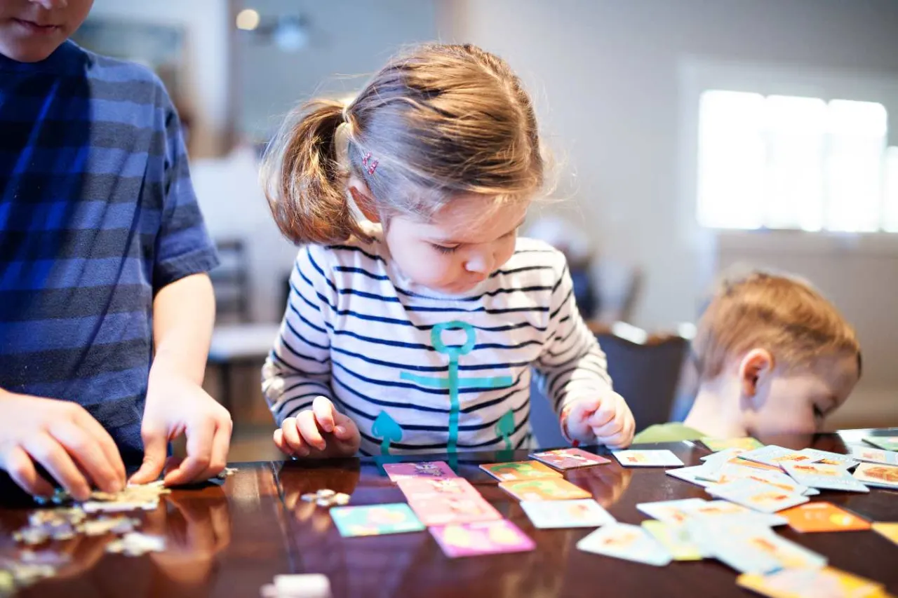 Dzieci układają karty, tworząc obrazkową zagadkę dla dziecka.
