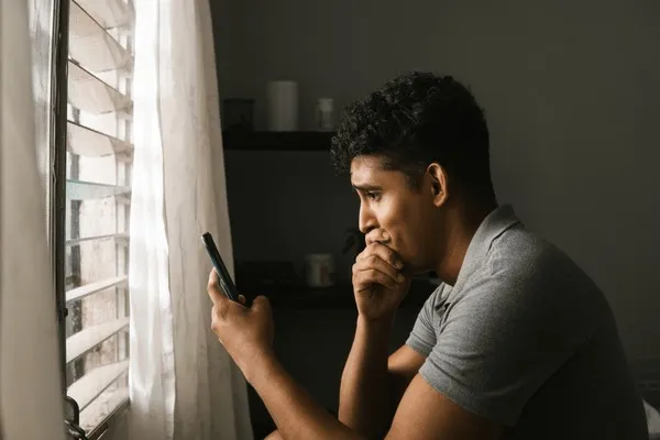 Osoba zmartwiona patrząca na ekran telefonu z wiadomościami