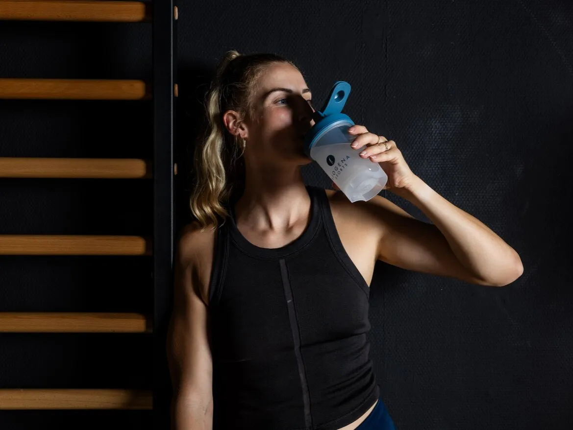 osoba pijąca napój z shakerem na siłowni