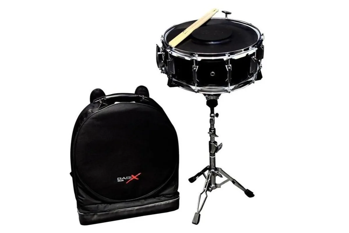 Czarny werbel na statywie z pałeczkami, obok torba na instrument. Gotowy do gry na werblu!