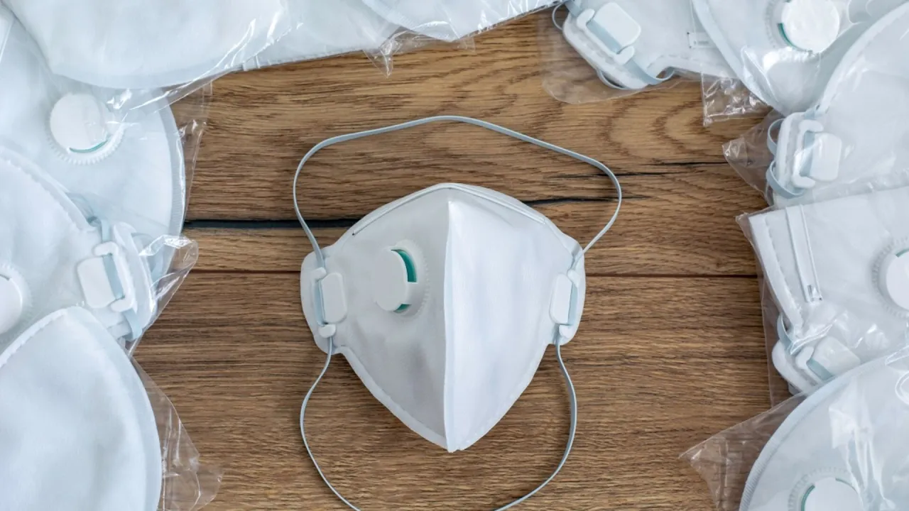 Białe maseczki ochronne z filtrem, ułożone na drewnianym tle. Czy maseczki chronią przed smogiem?