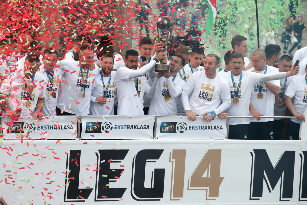 Piłkarze świętują, trzymając puchar i konfetti. Wszyscy w białych koszulkach z napisem 