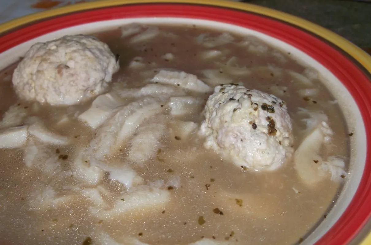 Dwa pulchne kluski pływają w aromatycznym bulionie z flakami. To właśnie takie kluski najczęściej dodajemy do flaków, by wzbogacić smak.