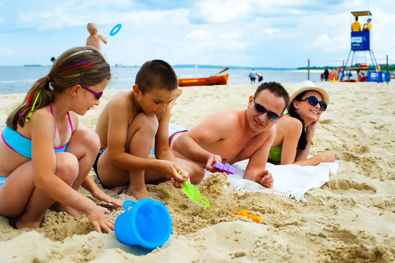 Rodzina buduje zamek z piasku na plaży w Świnoujściu. To świetne świnoujście atrakcje dla dzieci i dorosłych.