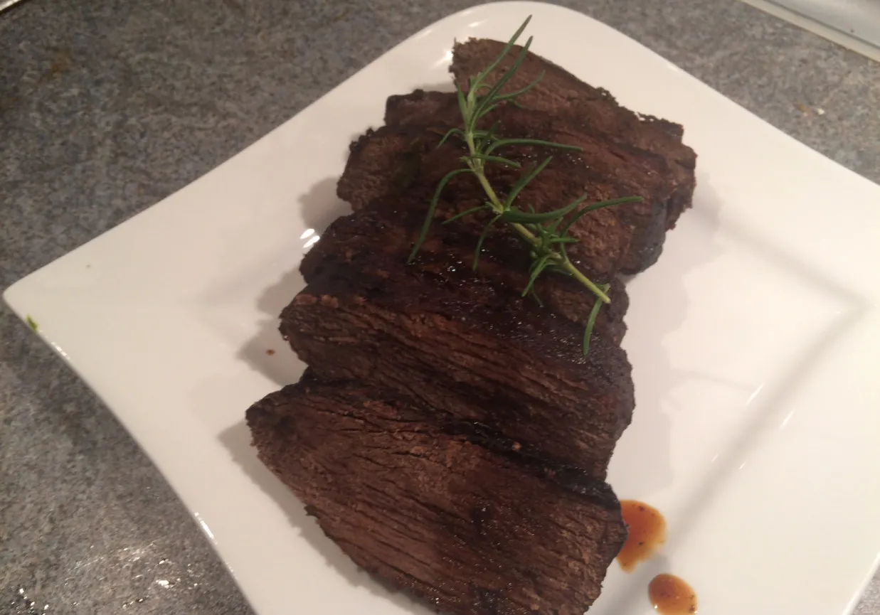 Pokrojony schab z jelenia, idealny do przyrządzenia na wiele sposobów. Ten soczysty kawałek mięsa, ozdobiony gałązką rozmarynu, zachęca do odkrycia, jak przygotować schab z jelenia.