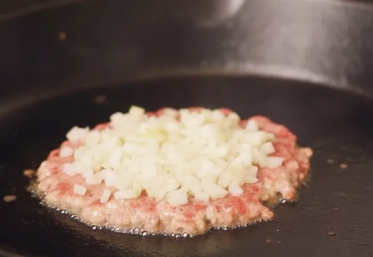 dociskanie burgera szpatułką na patelni z przekreśleniem