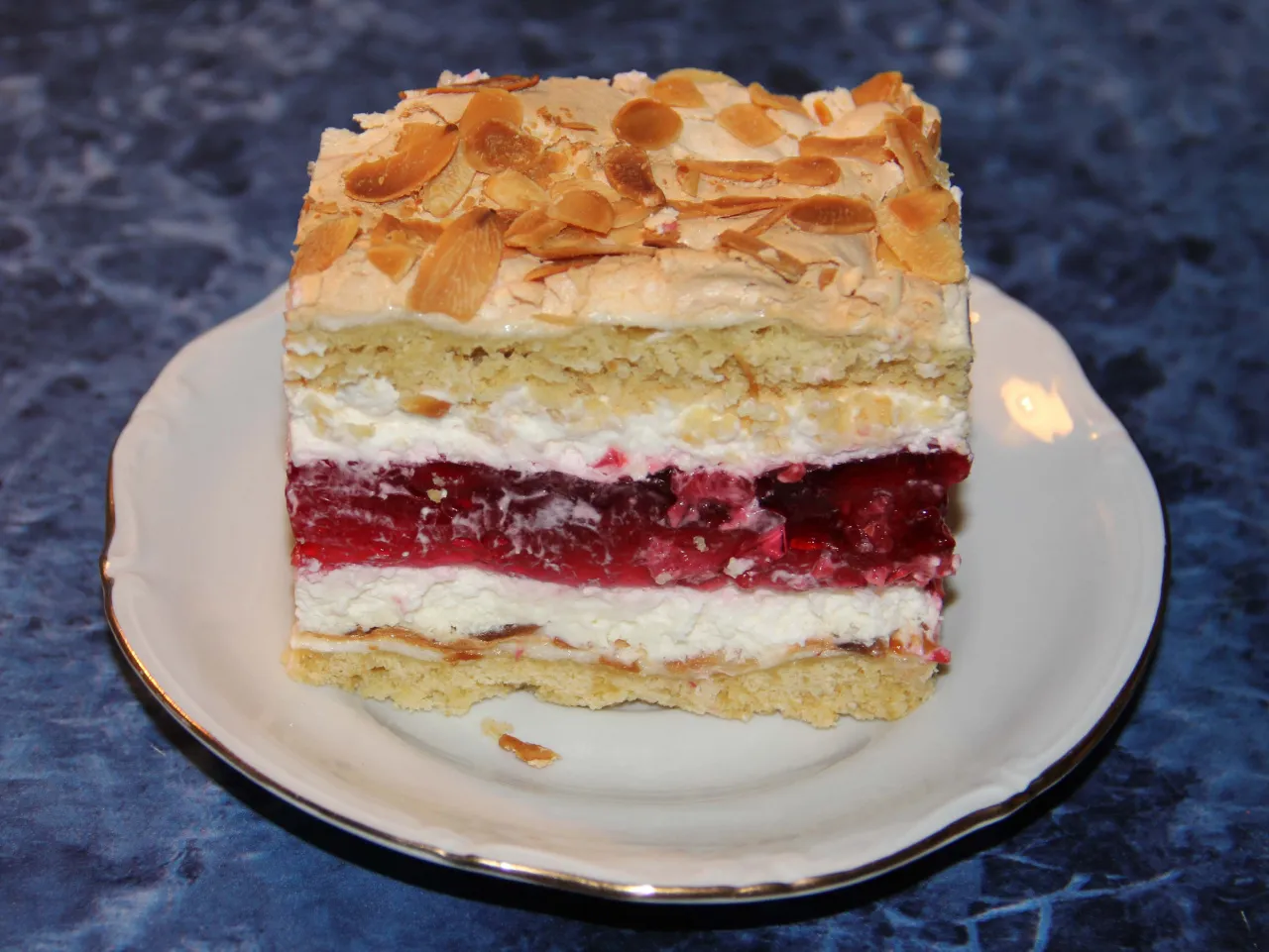 Pyszny kawałek ciasta z galaretką malinową i bezą, posypany płatkami migdałów. Czy malinową chmurkę można mrozić?