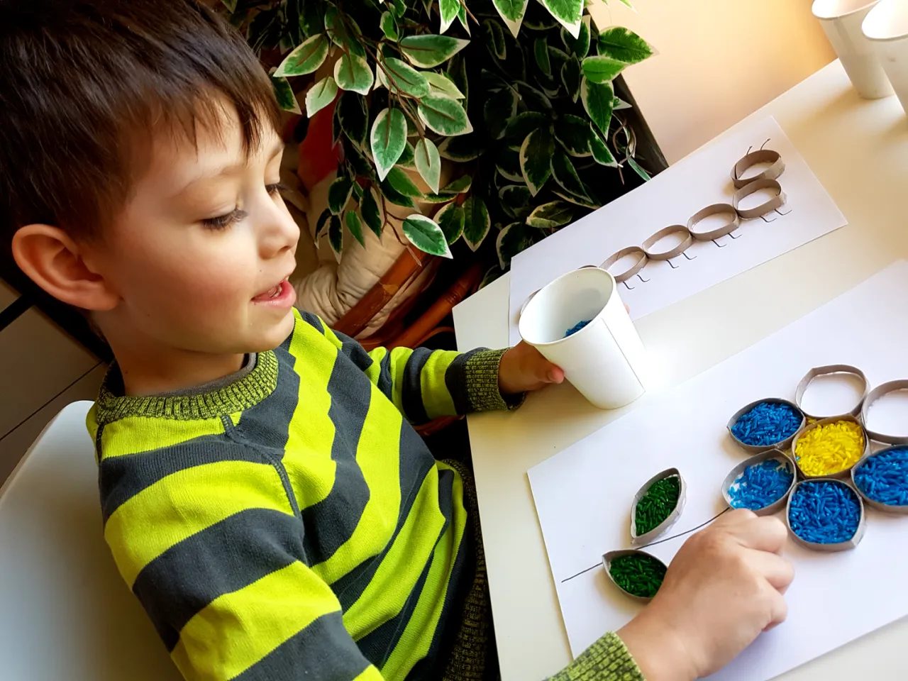 dziecko bawiące się w skrzyni z kolorowym ryżem sensorycznym