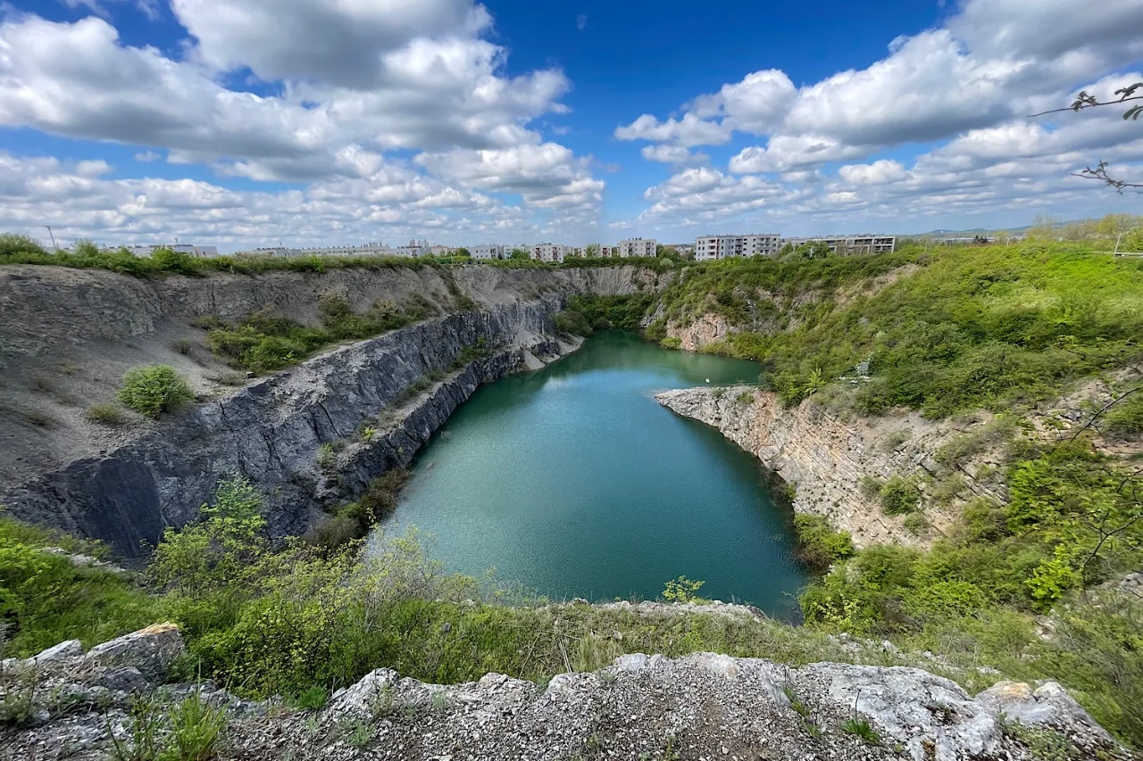 Malowniczy zalew w kamieniołomie, kt&oacute;ry stał się rezerwat przyrody Ślichowice. Woda lśni pod błękitnym niebem z chmurami.