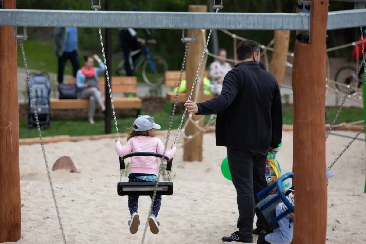 Ojciec z dzieckiem na placu zabaw, symbolizujący pozytywne relacje i dobro dziecka