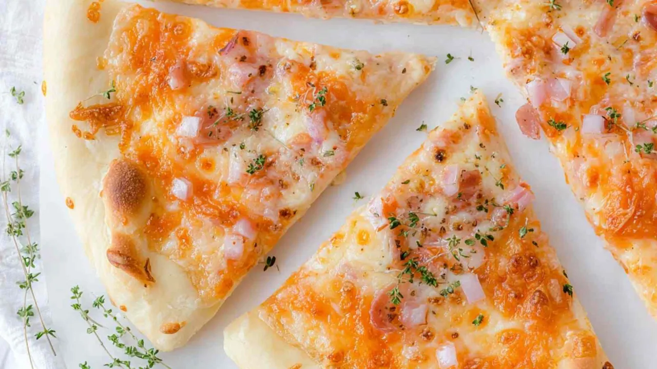 Kawałki pysznej pizzy bez drożdży, z ciągnącym się serem, kawałkami szynki i cebuli, posypane świeżym tymiankiem.