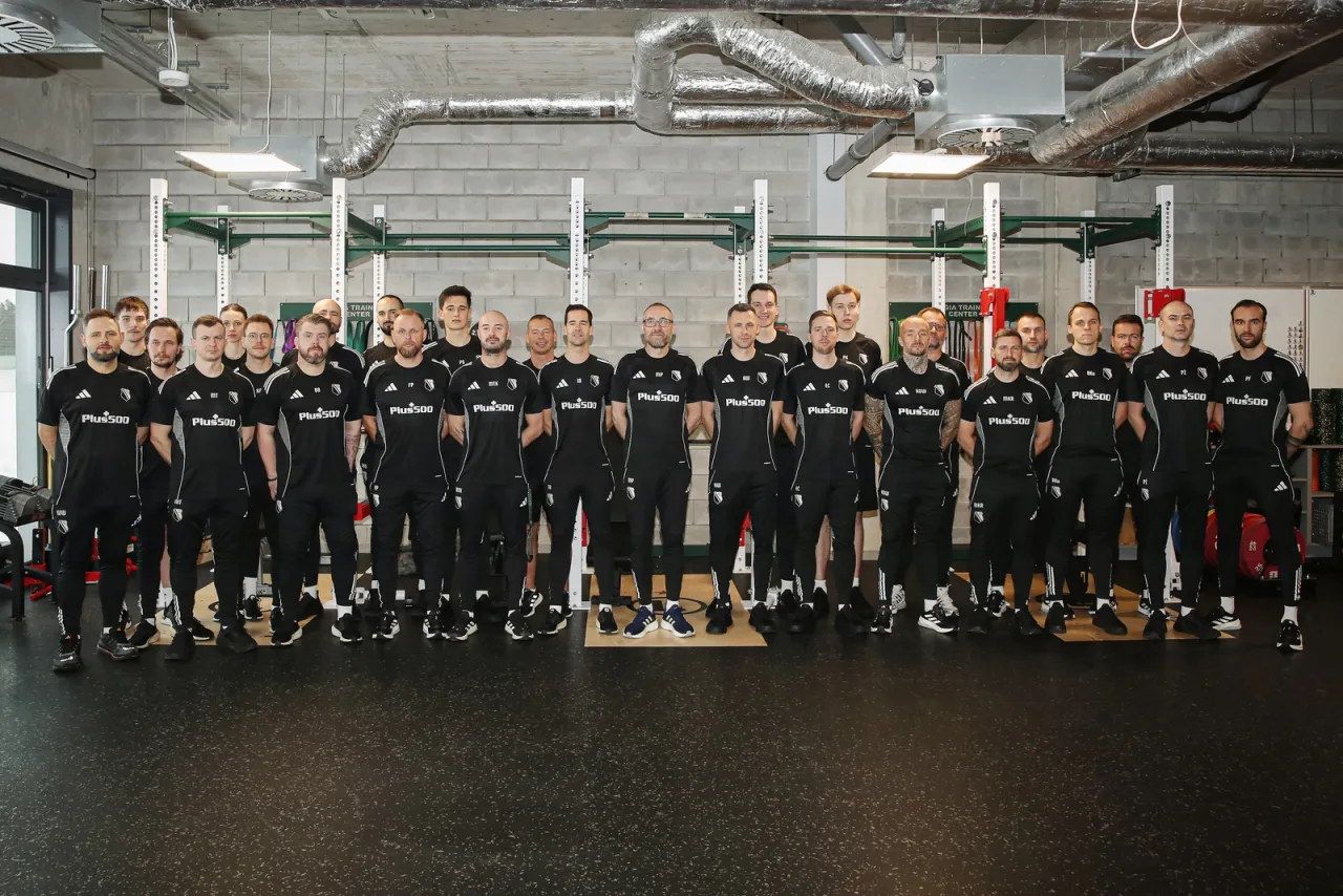 Legia Warszawa zawodnicy w strojach treningowych pozują do zdjęcia w siłowni.