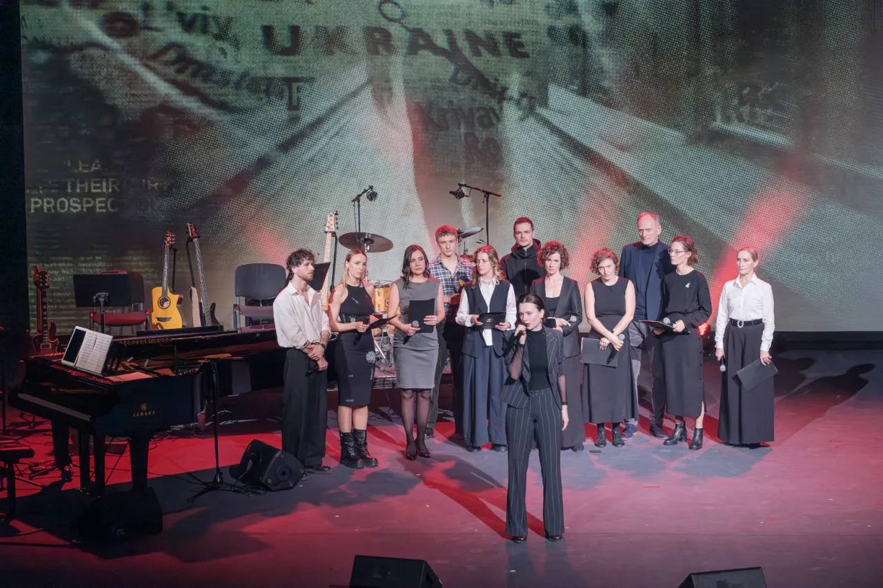 Grupa artyst&oacute;w na scenie, gdzie odbywa się koncert dla Ukrainy. W tle ekran z napisem 