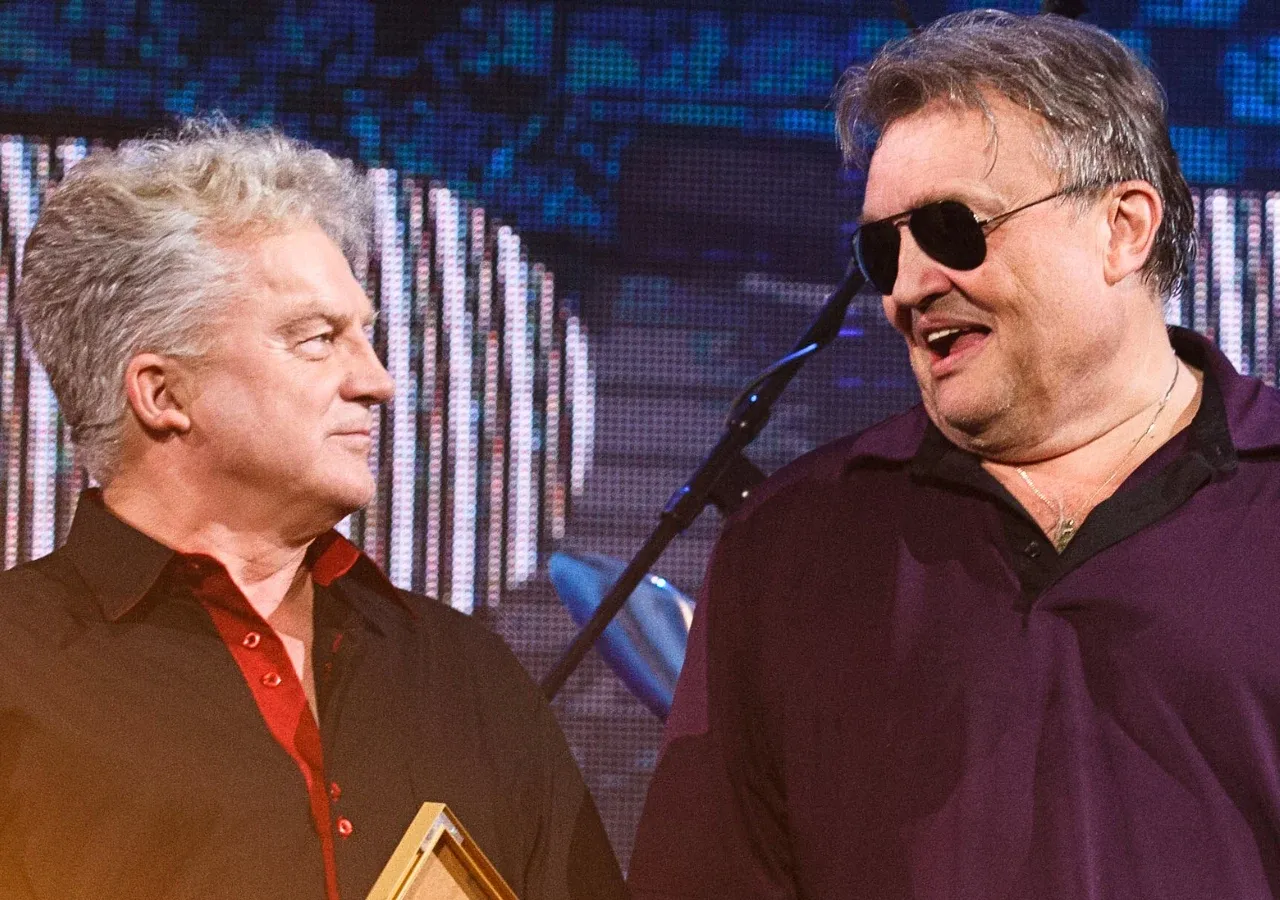 Dw&oacute;ch mężczyzn na scenie, jeden z siwymi włosami, drugi w okularach przeciwsłonecznych. Czy to oni, kto śpiewa Jolka Jolka?