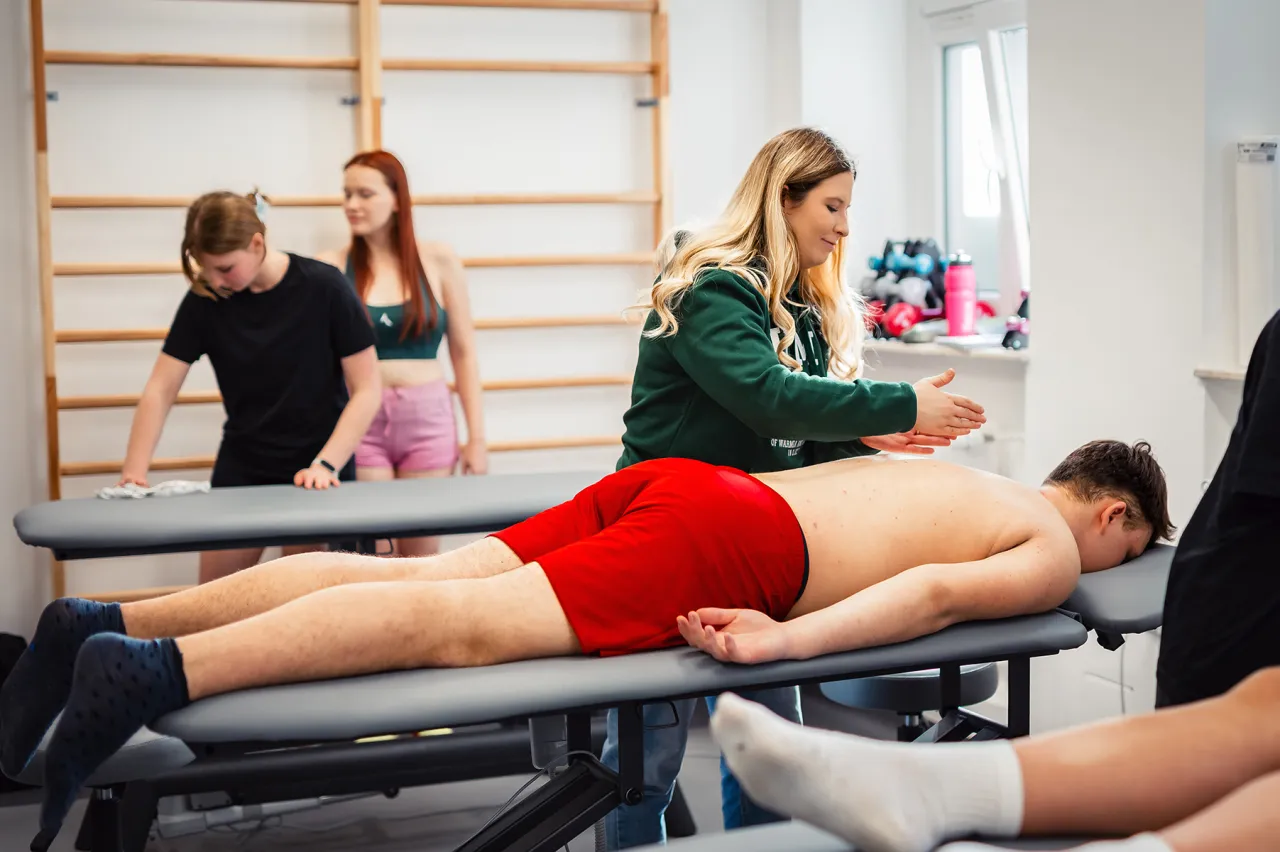 Studentka fizjoterapii ćwiczy masaż. Studia magisterskie fizjoterapia do kiedy? Nauka praktycznych umiejętności.