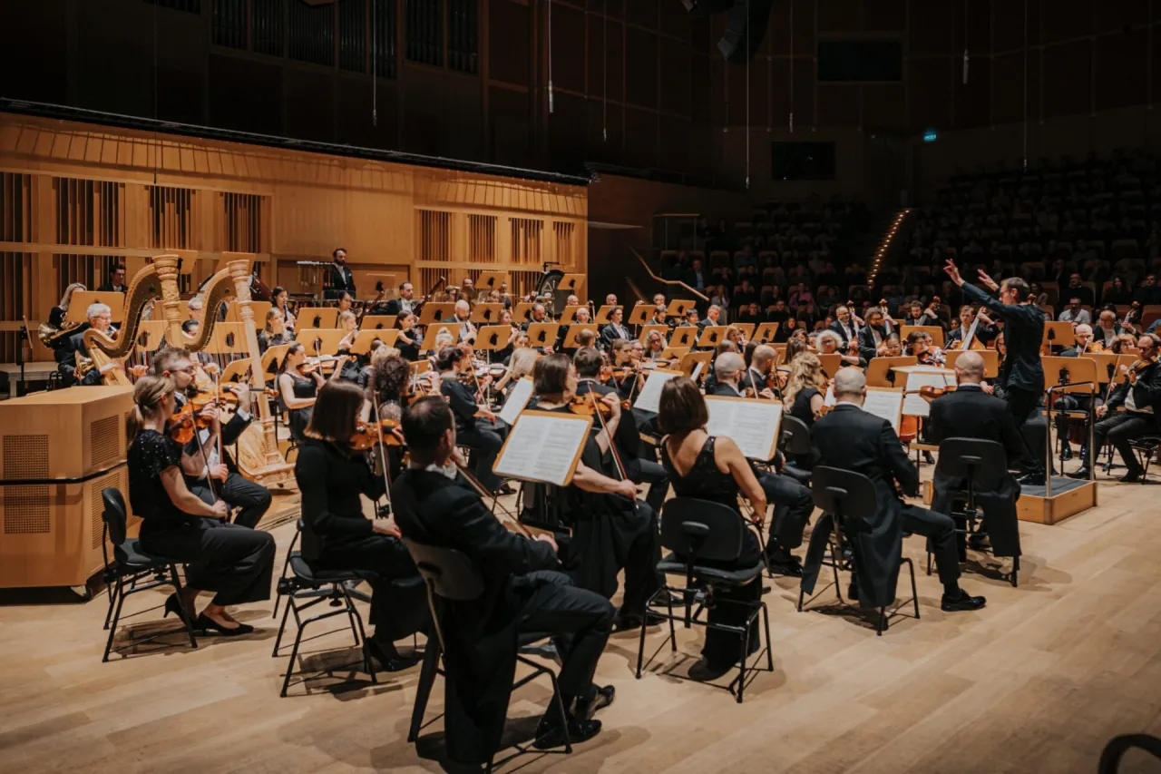 Orkiestra symfoniczna w pełnym składzie, dyrygent daje znak do rozpoczęcia. Zastanawiasz się, ile trwa koncert w filharmonii?
