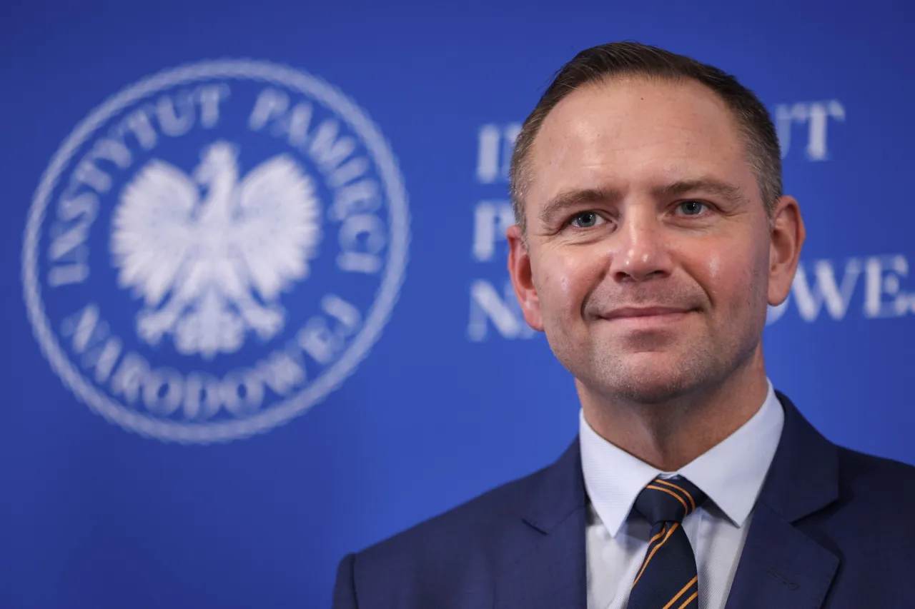 Karol Nawrocki, prezes IPN, uśmiecha się na tle instytucji. Jego popularność rośnie, co może tłumaczyć, dlaczego Karol Nawrocki wygrywa w najnowszych sondażach prezydenckich z marca 2026.