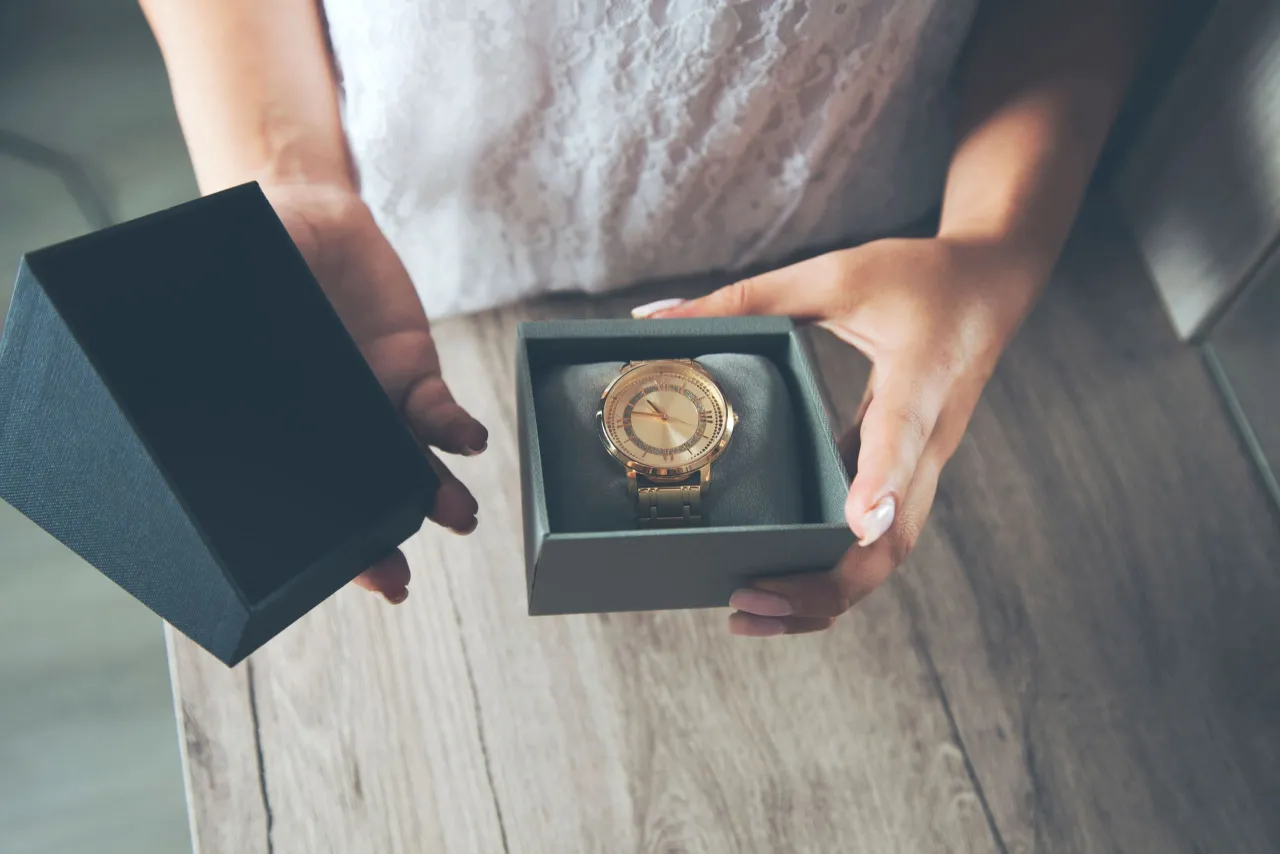 Złoty zegarek w pudełku, piękny prezent. Dlaczego nie daje się zegarka na prezent? Może symbolizuje przemijający czas?