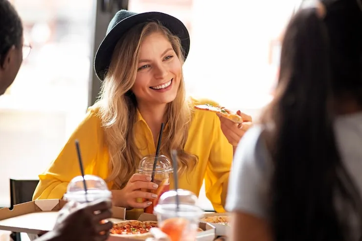 Zadowoleni klienci jedzący pizzę w restauracji