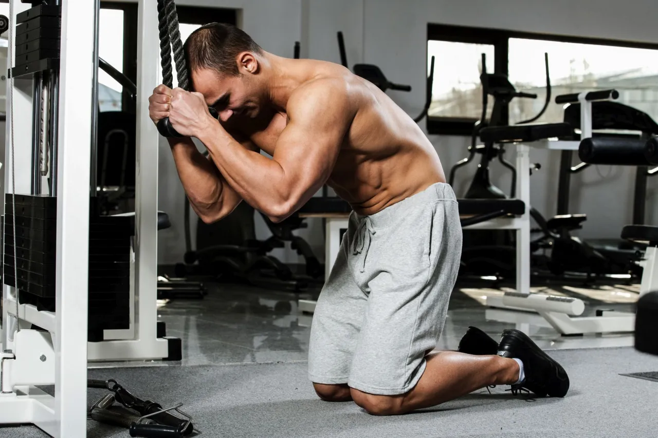 osoba ćwicząca brzuch z planem treningowym