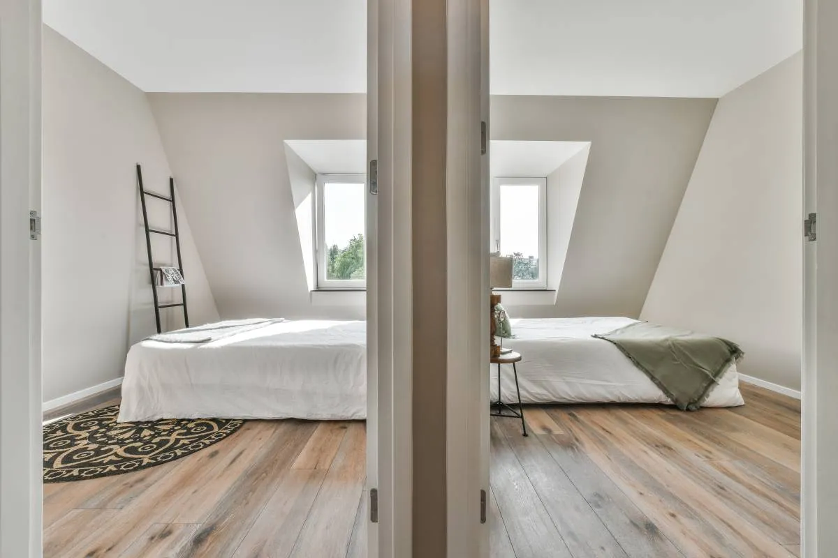 Dwa łóżka w pokoju z jednym oknem, pokazujące, jak podzielić pokój z jednym oknem na dwa mniejsze.