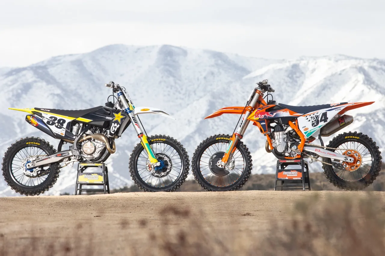 Dwa motocykle crossowe: czarny Husqvarna 450 z ż&oacute;łtymi akcentami i pomarańczowy KTM, stojące na tle ośnieżonych g&oacute;r.