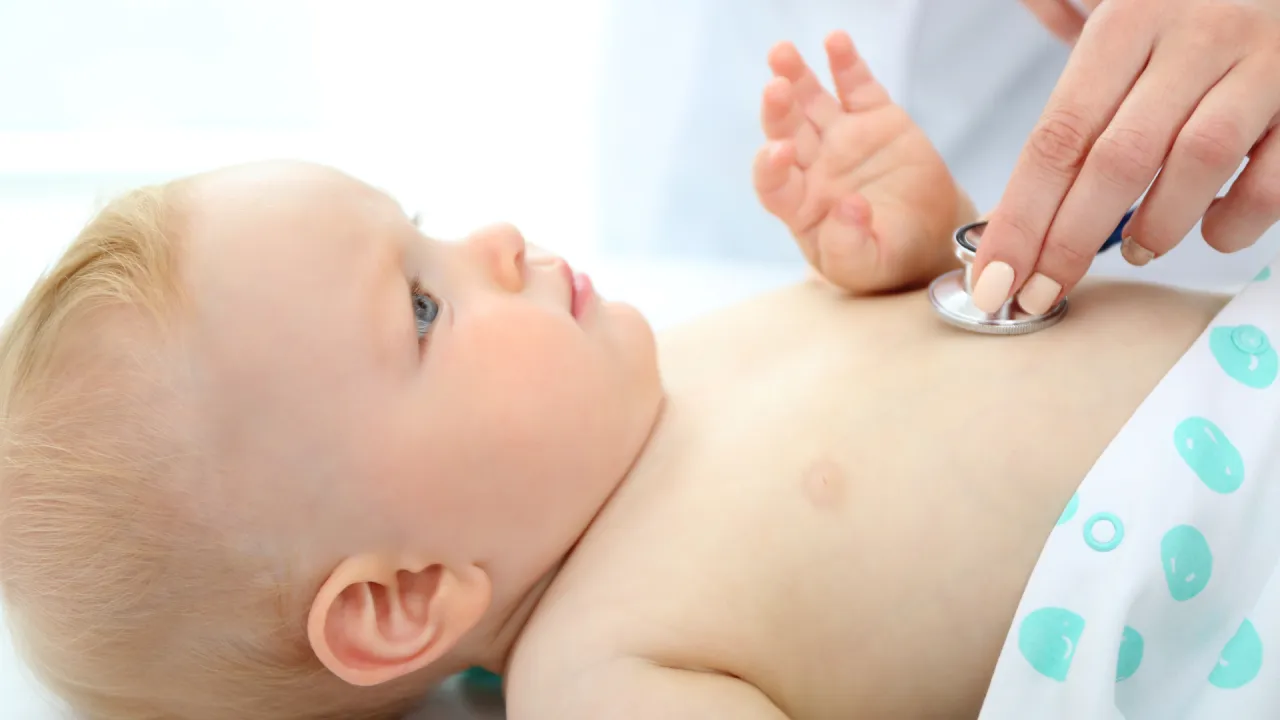 Lekarz osłuchuje niemowlę stetoskopem. Dziecko ma 7 punkt&oacute;w w skali Apgar, co świadczy o jego dobrym stanie.