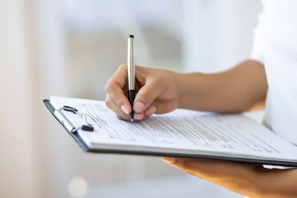 osoba wypełniająca formularz, biurko z dokumentami, długopis