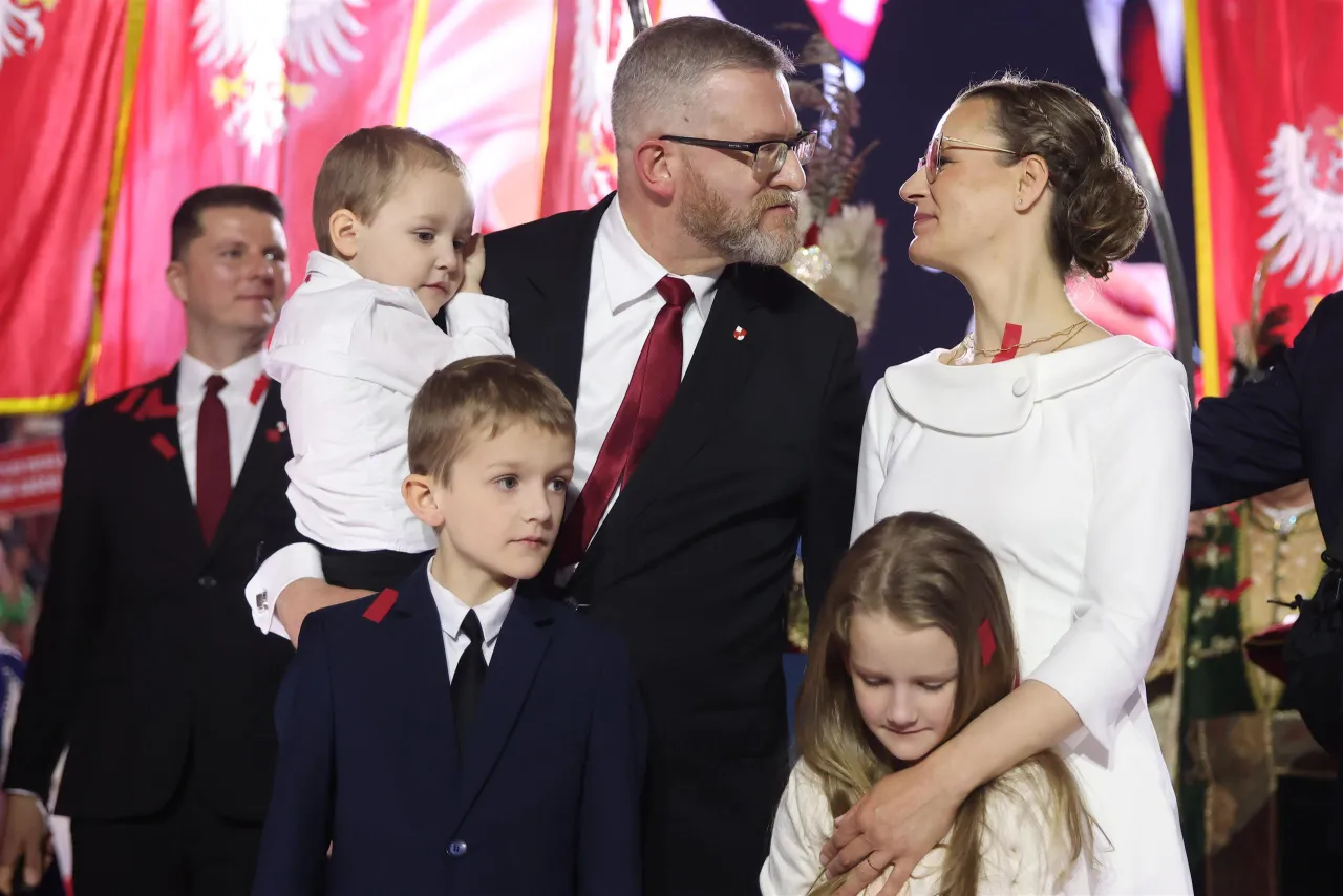 Rodzina z dziećmi na tle flagi. Czy Grzegorz Braun ma dzieci? Na zdjęciu widać jego córkę i dwóch synów.