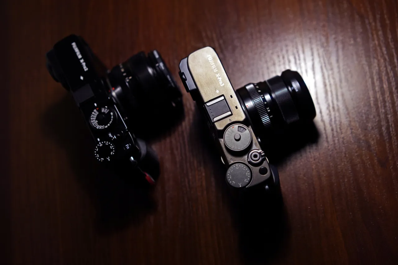 Dwa aparaty Fujifilm, w tym aparat fujifilm lustrzanka X-Pro3, leżą na drewnianym blacie.